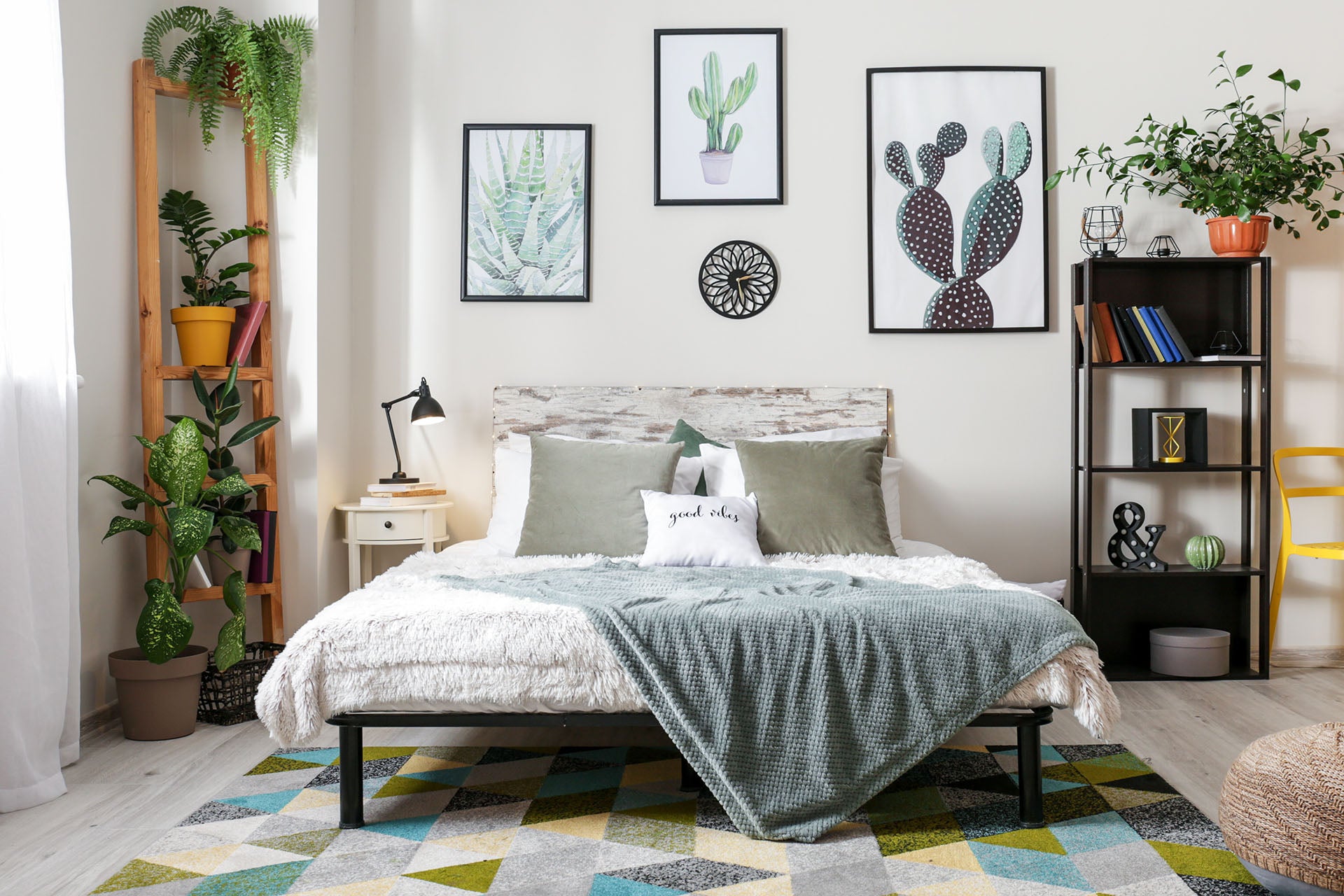 Double bed with plant pots in background, shelving unit and wall art.